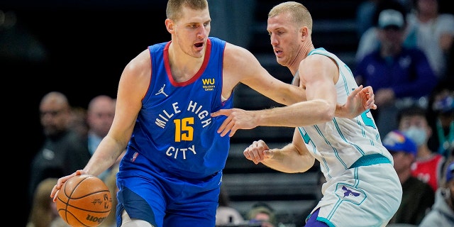 Denver Nuggets center Nikola Jokic (15) goes to the basket against Charlotte Hornets center Mason Plumlee, destra, during the first half of an NBA basketball game on Monday, marzo 28, 2022, a Charlotte, N.C.