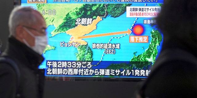 People walk along a sidewalk past a TV displaying a news program on North Korea's missile launch Thursday, March 24, 2022, in Tokyo.