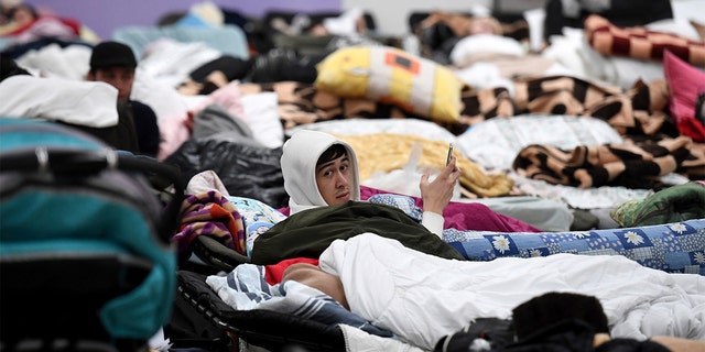 A man looks up from his cot, at a reception center for displaced persons from Ukraine at the border crossing in Korczowa, Poland, Saturday, March 5, 2022. (Olivier Douliery, Pool Photo via AP)