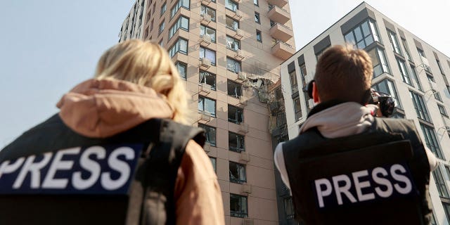 Journalists work near damaged buildings hit in a military strike, amid Russia's invasion of Ukraine, in Shevchenkivskyi district in Kyiv, Ukraine March 23, 2022.
