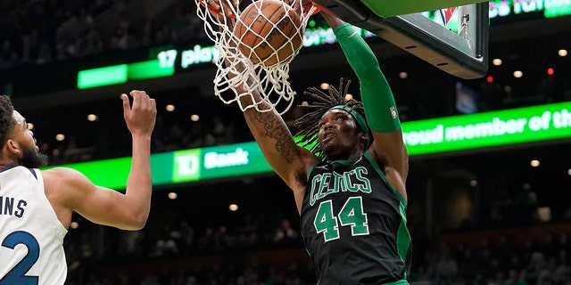 Boston Celtics center Robert Williams III (44) sinks the ball as Minnesota Timberwolves center Karl-Anthony Towns (32), left, tries to defend in the first half of an NBA basketball game, Sunday, March 27, 2022, in Boston.