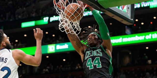 Boston Celtics center Robert Williams III (44) sinks the ball as Minnesota Timberwolves center Karl-Anthony Towns (32), left, tries to defend in the first half of an NBA basketball game, Sunday, March 27, 2022, in Boston.