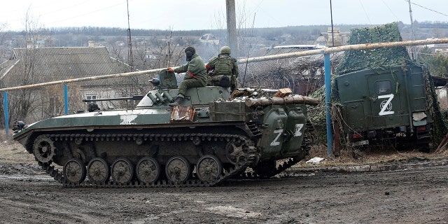 Service members of pro-Russian troops in uniforms without insignia drive an armoured vehicle with the symbol "Z" painted on its side in the separatist-controlled village of Bugas during Ukraine-Russia conflict in the Donetsk region, Ukraine March 6, 2022.