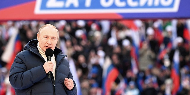 Russian President Vladimir Putin delivers a speech during a concert marking the eighth anniversary of Russia's annexation of Crimea at Luzhniki Stadium in Moscow, March 18, 2022. The banner reads: "For Russia." Sputnik/Sergey Guneev/Kremlin via REUTERS