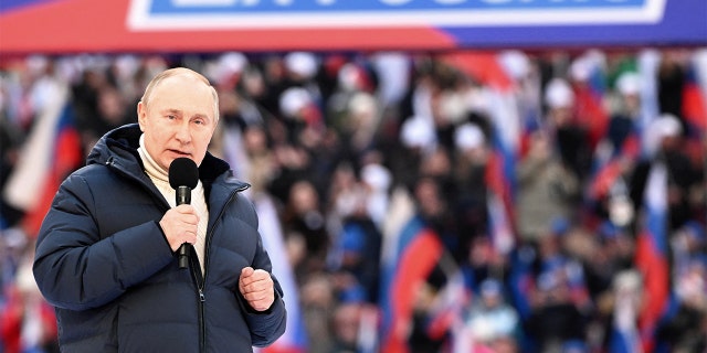 Russian President Vladimir Putin delivers a speech during a concert marking the eighth anniversary of Russia's annexation of Crimea at Luzhniki Stadium in Moscow, March 18, 2022. The banner reads: "For Russia." Sputnik/Sergey Guneev/Kremlin via REUTERS
