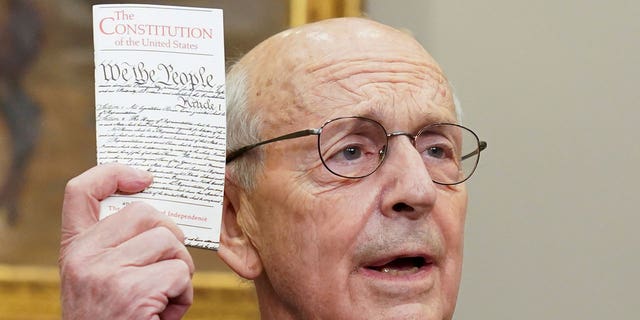 U.S. Supreme Court Justice Stephen Breyer holds up a copy of the U.S. Constitution as Breyer announces he will retire at the end of the court's current term, at the White House in Washington, Jan. 27, 2022. 