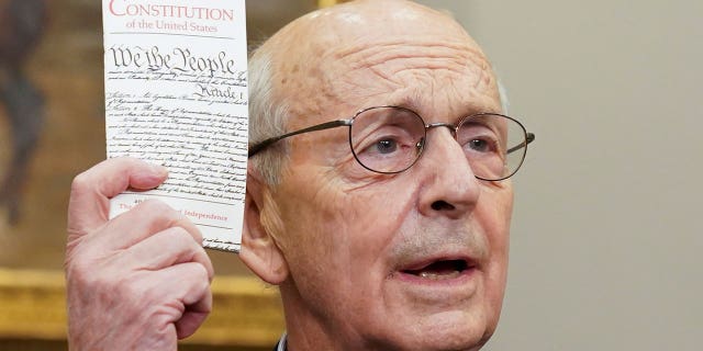 U.S. Supreme Court Justice Stephen Breyer holds up a copy of the U.S. Constitution as Breyer announces he will retire at the end of the court's current term, at the White House in Washington, U.S., January 27, 2022.