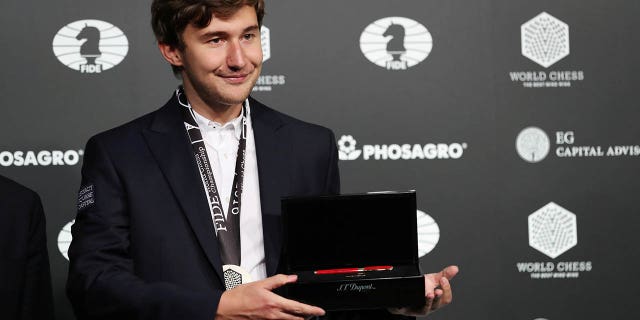 Sergey Karjakin of Russia wears a medal and holds a commemorative pen after losing to Magnus Carlsen of Norway at the 2016 World Chess Championship match in New York, Nov. 30, 2016.