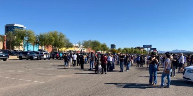 A crowd stands in the parking lot of the Tanger Outlets mall in Glandale, Arizona after a shooting injured at least one person. 