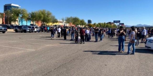 A crowd stands in the parking lot of the Tanger Outlets all in Glandale, Arizona after a shooting injured at least one person.