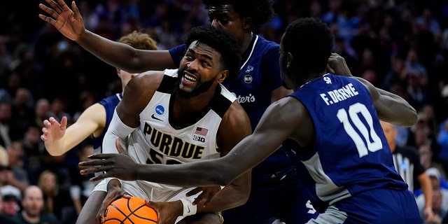 Purdue's Trevion Williams, left, tries to get a shot past Saint Peter's Clarence Rupert, center, and Fousseyni Drame during the second half of a college basketball game in the Sweet 16 round of the NCAA tournament, Friday, March 25, 2022, in Philadelphia.