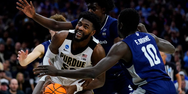 Purdue's Trevion Williams, left, tries to get a shot past Saint Peter's Clarence Rupert, center, and Fousseyni Drame during the second half of a college basketball game in the Sweet 16 round of the NCAA tournament, Friday, March 25, 2022, in Philadelphia.