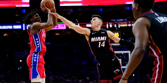 Philadelphia 76ers' Tyrese Maxey, left, goes upper a shot against Miami Heat's Tyler Herro, center, during the second half of an NBA basketball game, Monday, March 21, 2022, in Philadelphia.