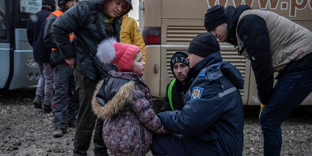 A local police officer helps a Ukrainian refugee girl who was apparently separated from her mother on the Moldova- Ukraine border.