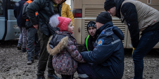 Half of Ukraine's children displaced: 'A grim milestone' 2 A local police officer helps a Ukrainian refugee girl who was apparently separated from her mother on the Moldova- Ukraine border.