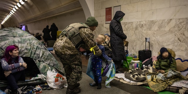 A Ukrainian soldier visits his son who is taking shelter in the lower level of a Kyiv metro station during Russian artillery strikes in Kyiv, Ukraine, on Wednesday, March 2, 2022.