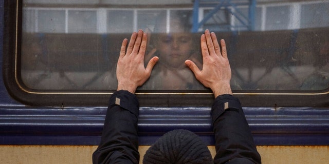Aleksander, 41, presses his hands against the window as he greets his daughter Anna, 5, on a train in Lviv at the Kyiv airport, Ukraine, Friday, March 4, 2022. Aleksander must stay behind to fight the war. As his family had left the country to seek refuge in a nearby land.