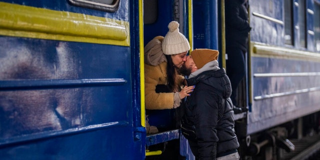 Stanislav, 40, kisses his wife Anna, 35, on a train to Lviv as they say goodbye at the Kyiv station, Ukraine, Thursday, March 3. 2022. Stanislav is staying to fight while his family is leaving the country to seek refuge in a neighboring country. (AP Photo/Emilio Morenatti) 