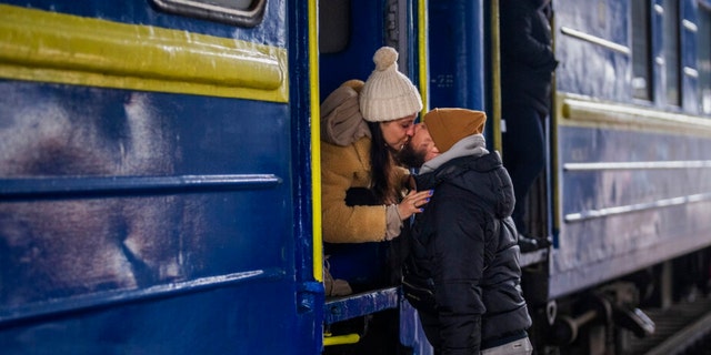 Stanislav, 40, kisses his wife Anna, 35, on a train to Lviv as they say goodbye at the Kyiv station, Ukraine. Stanislav is staying to fight while his family is leaving the country to seek refuge in a neighboring country.