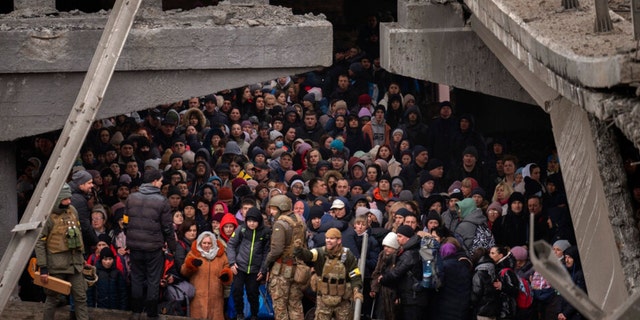 Ukrainians crowd under a destroyed bridge as they try to flee crossing the Irpin river
