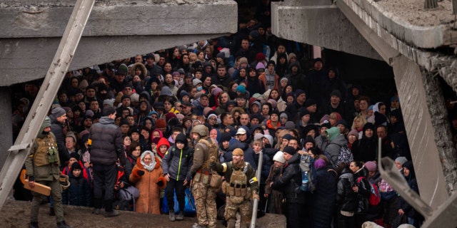 Ukrainians crowd under a destroyed bridge as they try to flee crossing the Irpin river in the outskirts of Kyiv, Ukraine, Saturday, March 5, 2022. (AP Photo/Emilio Morenatti)