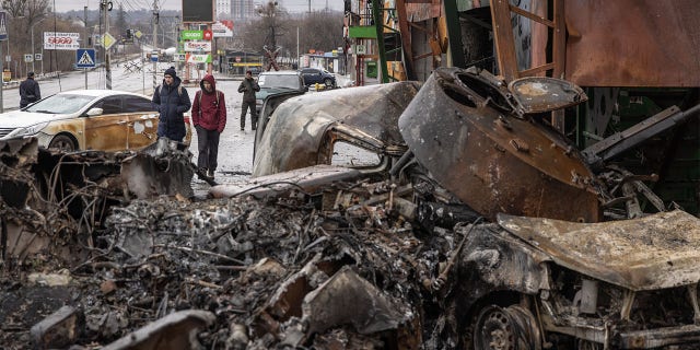 People walk past a destroyed Russian military vehicle at a frontline position on March 03, 2022 in Irpin, Ukraine.