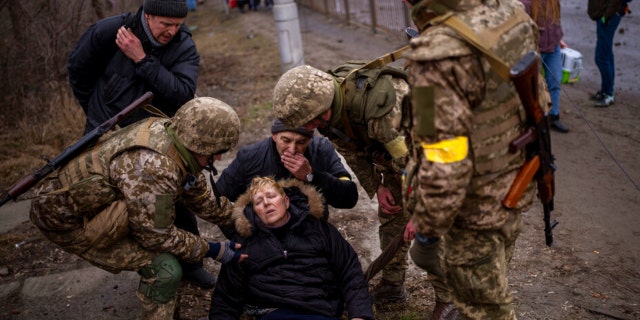 A semi-conscious woman is attended to by Ukrainian soldiers after crossing the Irpin river as fleeing the city in the outskirts of Kyiv, Ukraine, Saturday, March 5, 2022.
