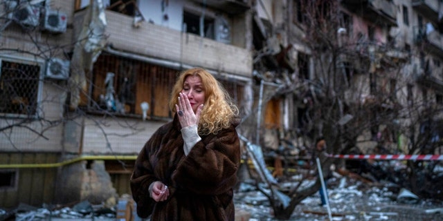 2022年2月25日星期五，纳塔利·塞夫里乌科娃（Natali Sevriukova）在乌克兰基辅市遭到火箭袭击后，在她的房子旁边做出反应。（美联社照片/Emilio Morenatti）