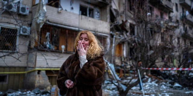 Natali Sevriukova reacts next to her house following a rocket attack the city of Kyiv, Ukraine, Friday, Feb. 25, 2022.  