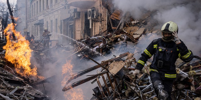Responders are seen at the scene after a building destroyed by a Russian rocket attack in downtown Kharkiv