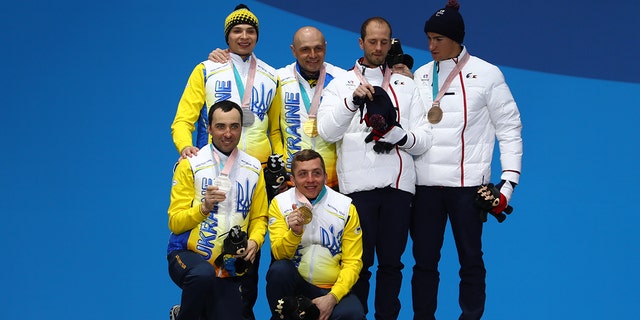 Silver medalist Oleksandr Kazik of Ukraine and his guide Sergiy Kucheryaviy, gold medalist Vitaliy Luk'yanenko of Ukraine and his guide Ivan Marchyshak, and bronze medalist Anthony Chalencon of France and his guide Simon Valverde celebrate during the medal ceremony for Men's 15 km Visually Impaired Biathlon on day eight of the PyeongChang 2018 Paralympic Games on March 17, 2018, in Pyeongchang-gun, Corea del Sur.