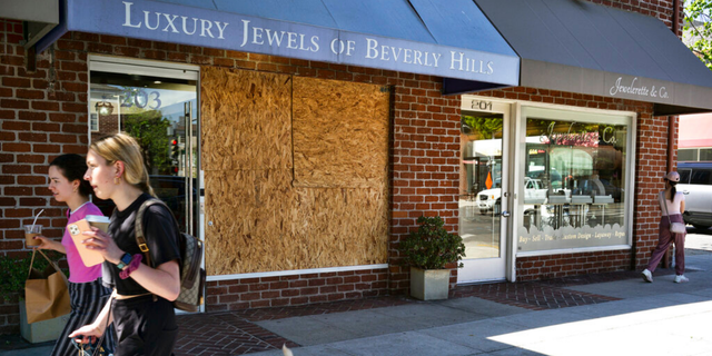 Shoppers walk past a boarded up Luxury Jewels of Beverly Hills on Wednesday, March 23, 2022 in Beverly Hills, Calif. 