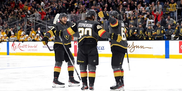 Vegas Golden Knights defenseman Shea Theodore (27), center Chandler Stephenson (20) and right wing Evgenii Dadonov (63) celebrate Dadonov's goal against the Nashville Predators during the second period of an NHL hockey game Thursday, Maart 24, 2022, in Las Vegas.