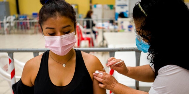A healthcare worker administers a booster dose of a COVID 19 vaccine at a temporary vaccine center in Guatemala City, Dinsdag, Maart 1, 2022. 