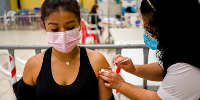 A healthcare worker administers a booster dose of a COVID 19 vaccine at a temporary vaccine center in Guatemala City, Tuesday, March 1, 2022. 