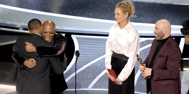 Will Smith accepts the best actor award for "King Richard" from Samuel L. Jackson, Uma Thurman and John Travolta during the 94th Annual Academy Awards on March 27, 2022, in Hollywood, California.