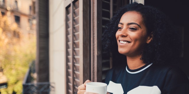 Woman drinking coffee with a smile. 