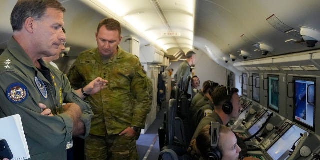 Admiral John C. Aquilino, left, commander of the U.S. Indo-Pacific Command (INDOPACOM), looks at videos of Chinese structures and buildings on board a U.S. P-8A Poseidon reconnaissance plane flying at the Spratly group of islands in the South China Sea Sunday, March 20, 2022.Â