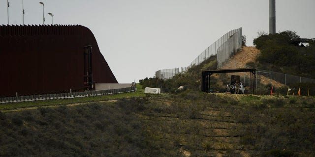 Jan, 12, 2022: US Border Patrol agents (R) monitor a section of the US-Mexico border wall between San Diego and Tijuana in San Diego County, California. (Photo by PATRICK T. FALLON/AFP via Getty Images)