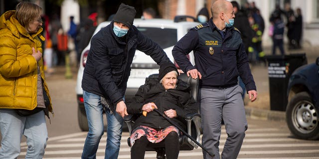 La policía fronteriza empuja a una anciana en una silla de oficina después de huir con su familia del conflicto de la vecina Ucrania, en la frontera rumano-ucraniana, en Siret, Rumania, el 27 de febrero de 2022.