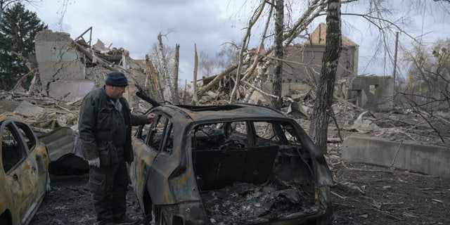 A man stands next to a burnt car near a cultural and community centre, which locals said was destroyed by recent shelling, as Russia's invasion of Ukraine continues, in the settlement of Byshiv in the Kyiv region, Ukraine on March 4, 2022.