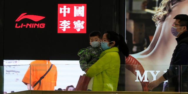 Visitors to a mall walk past signs of Chinese sports brand Li Ning on Wednesday, March 16, 2022, in Beijing.