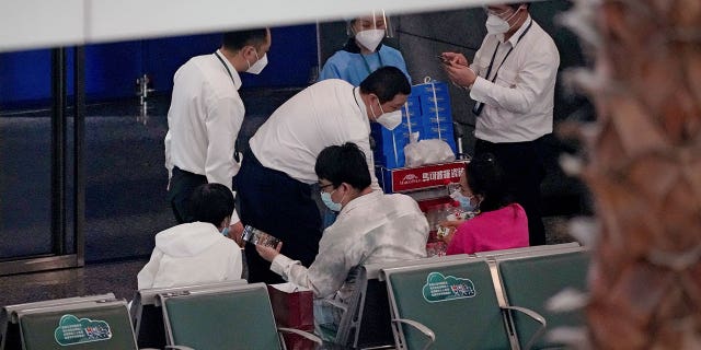 Martedì 22 marzo 2022 i lavoratori consegnano bevande alle persone in un'area transennata per i parenti delle vittime a bordo del volo China Eastern MU5735 all'aeroporto internazionale di Guangzhou Baiyun a Guangzhou, capitale della provincia del Guangdong della Cina meridionale.