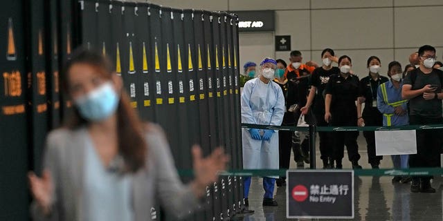 Workers and security personnel talk with a journalist reporting near a cordoned off area for the relatives of victims aboard China Eastern's flight MU5735, in the Guangzhou Baiyun International Airport in Guangzhou, capital of south China's Guangdong Province, Tuesday, March 22, 2022. 