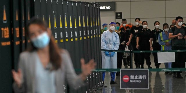 Lavoratori e personale di sicurezza chiacchierano con un giornalista che riferisce nei pressi di un'area transennata per i parenti delle vittime a bordo del volo China Eastern MU5735 all'aeroporto internazionale di Guangzhou Baiyun nella capitale provinciale Guangzhou del Guangdong (Cina meridionale), martedì 22 marzo 2022.