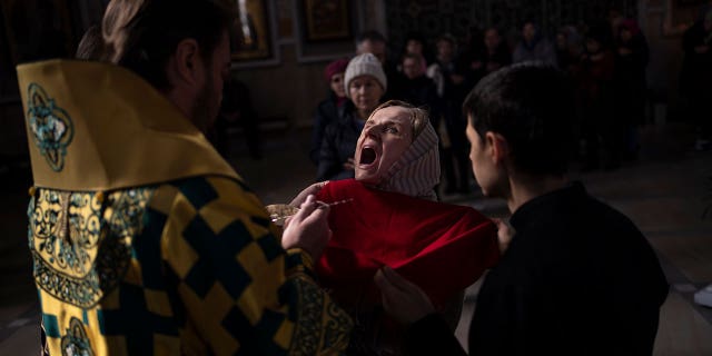 A woman receives communion inside the Transfiguration of Jesus Orthodox Cathedral, in Kyiv, Ukraine, Sunday, March 20, 2022.