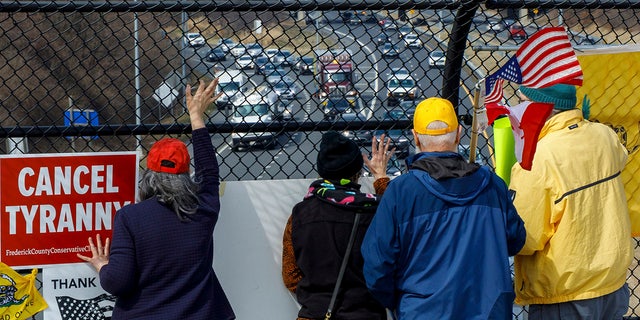 People watch from an overpass as trucks and other vehicles with the People Convoy of Truckers, protesting mandates and other issues, head South on Interstate I-270 Sunday, March 6, 2022, in Frederick, Md., toward the Capital Beltway. (AP Photo/Jon Elswick)