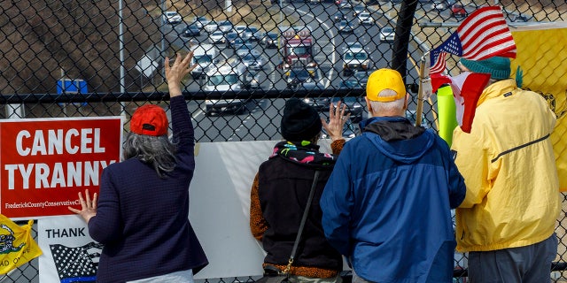 People watch from an overpass as trucks and other vehicles with the People Convoy of Truckers, protesting mandates and other issues, head South on Interstate I-270 Sunday, March 6, 2022, in Frederick, Md., toward the Capital Beltway. (AP Photo/Jon Elswick)