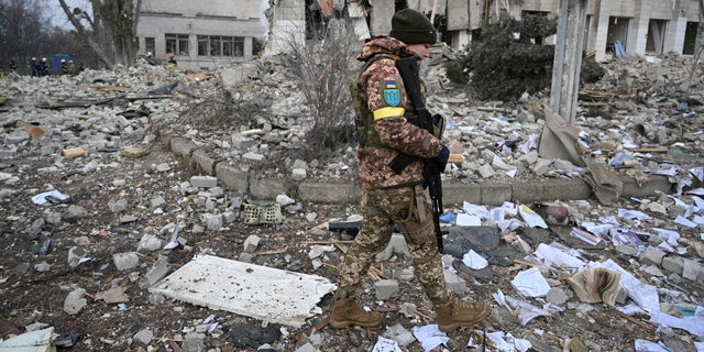 A Ukrainian service member walks near a school building destroyed by shelling in Zhytomyr, Ukraine, March 4, 2022, as Russia's invasion continues. 