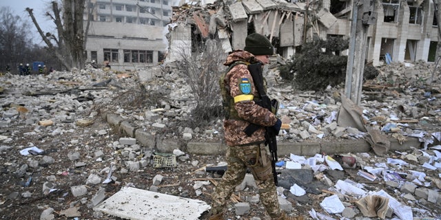 A Ukrainian service member walks near a school building destroyed by shelling in Zhytomyr, Ukraine, March 4, 2022, as Russia's invasion continues.